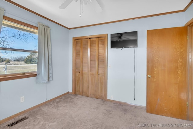 unfurnished bedroom featuring light colored carpet, a closet, visible vents, and crown molding