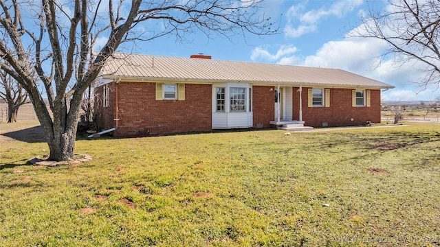 single story home with metal roof, a chimney, a front lawn, and brick siding