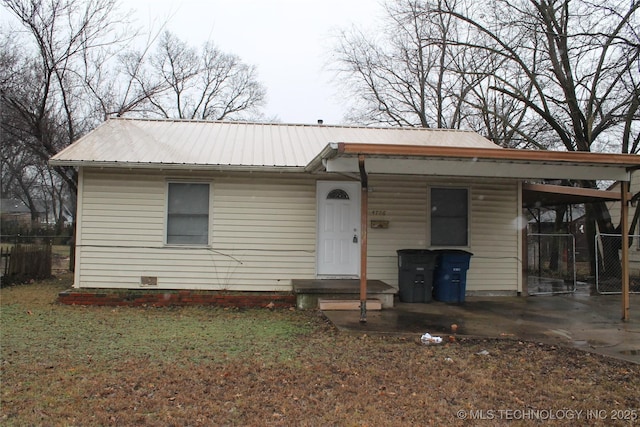 view of front facade featuring driveway, fence, metal roof, and an attached carport