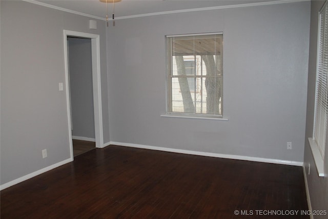 spare room featuring ornamental molding, baseboards, and wood finished floors