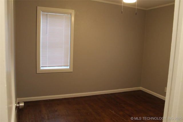 spare room with crown molding, baseboards, and dark wood-style flooring