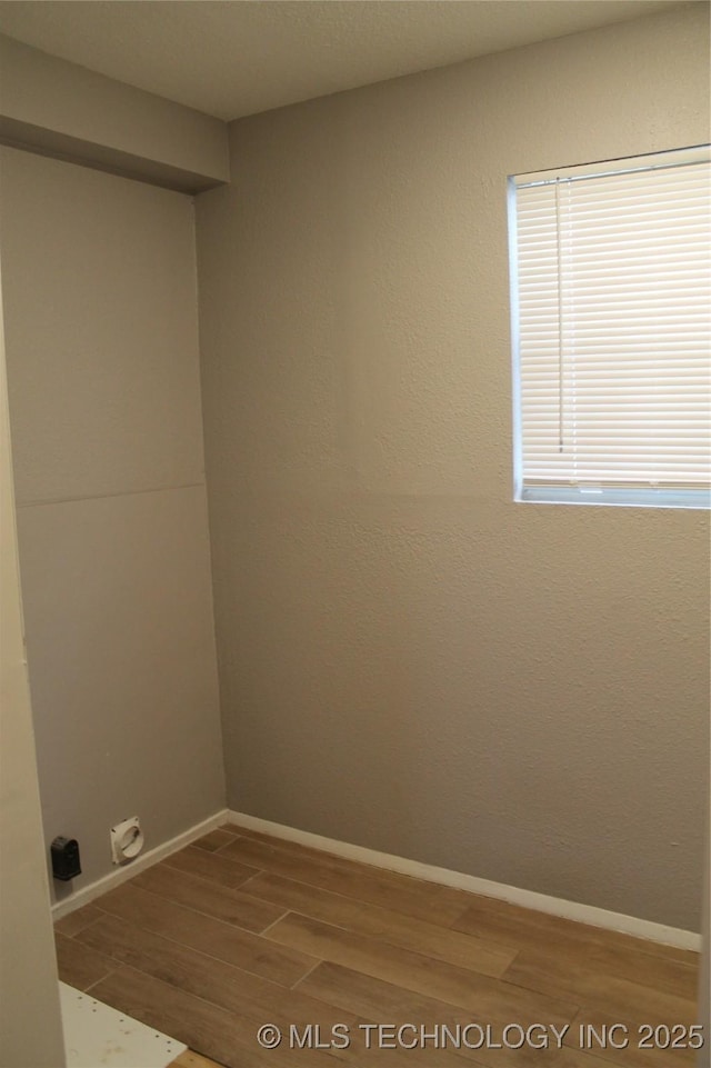 clothes washing area with laundry area, baseboards, and wood finished floors