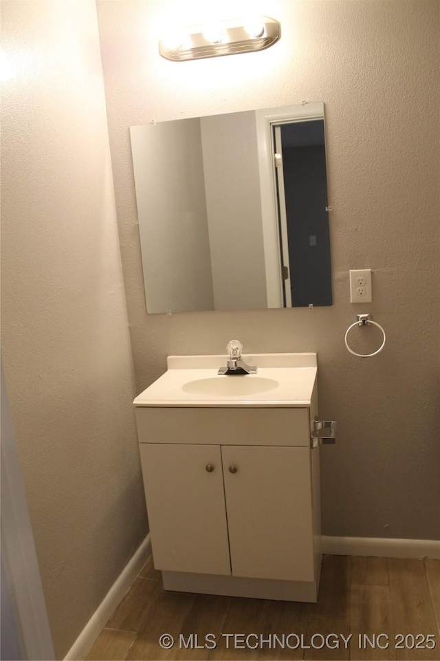 bathroom featuring vanity, baseboards, and wood finished floors