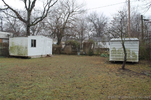 view of yard featuring a storage shed, fence, and an outdoor structure