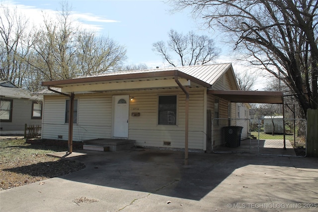 bungalow-style house featuring an attached carport, fence, concrete driveway, metal roof, and a gate