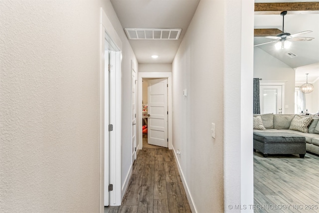 corridor with vaulted ceiling with beams, baseboards, visible vents, and wood finished floors