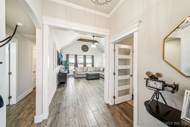 corridor featuring dark wood-type flooring, lofted ceiling, ornamental molding, and baseboards