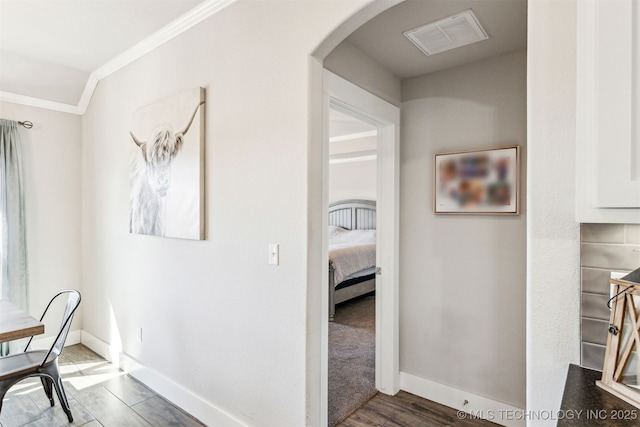 hallway with baseboards, visible vents, wood finished floors, and ornamental molding