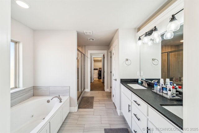 bathroom with double vanity, a stall shower, visible vents, a jetted tub, and a sink