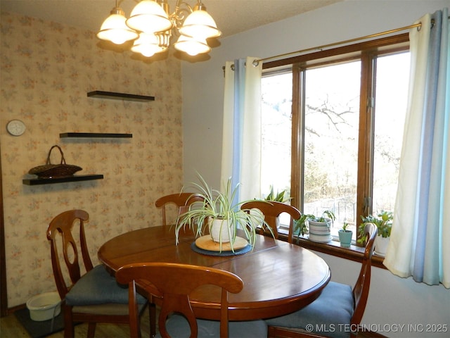 dining room with a chandelier and wallpapered walls