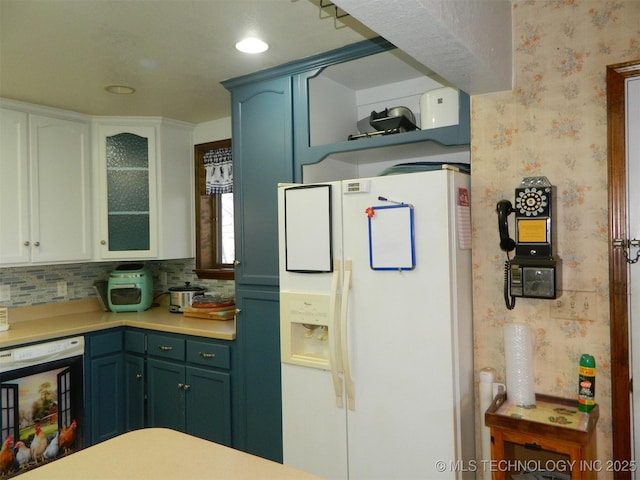 kitchen with wallpapered walls, beverage cooler, glass insert cabinets, light countertops, and white fridge with ice dispenser