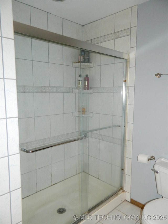 full bathroom featuring a stall shower, baseboards, and toilet