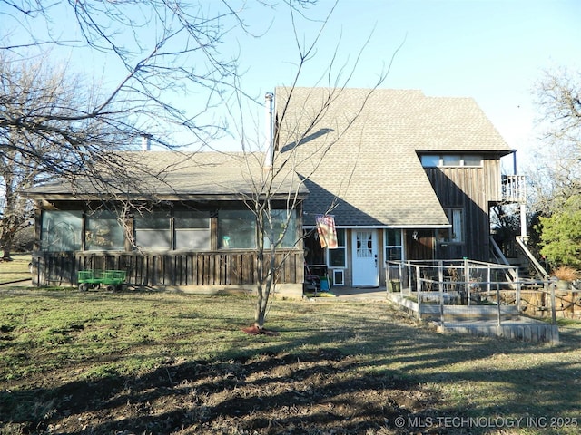 rear view of house featuring a sunroom, a shingled roof, a lawn, and a patio