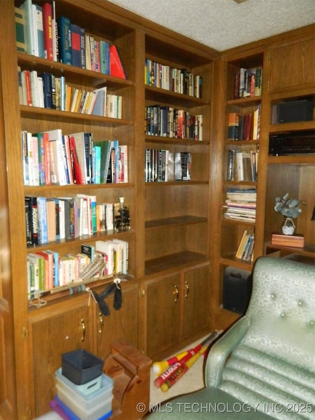 living area featuring a textured ceiling and wall of books