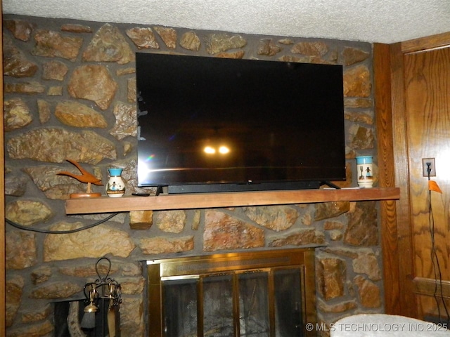 interior details with a textured ceiling and a stone fireplace