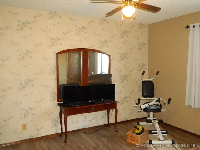 exercise room featuring wallpapered walls, ceiling fan, baseboards, and wood finished floors