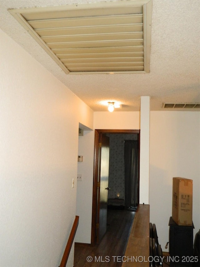 hallway featuring dark wood-style floors, visible vents, and a textured ceiling