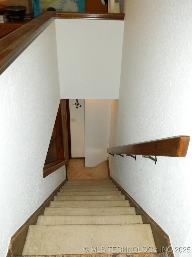 staircase featuring a textured wall