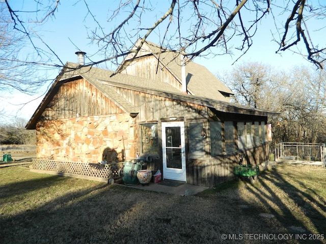 rear view of property with a shingled roof, a chimney, and a lawn