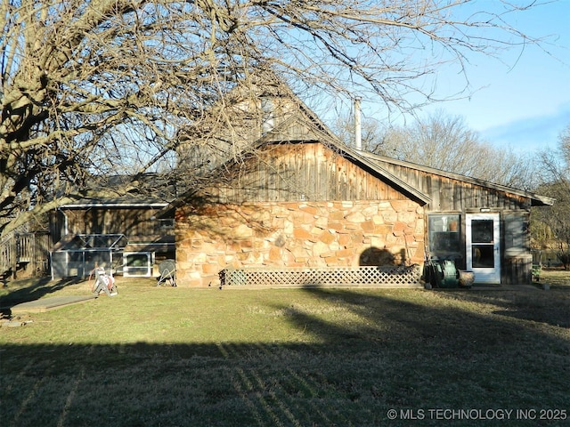 view of home's exterior featuring board and batten siding, stone siding, and a lawn