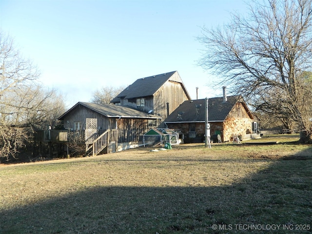 rear view of house with a yard, stairway, stone siding, and a wooden deck