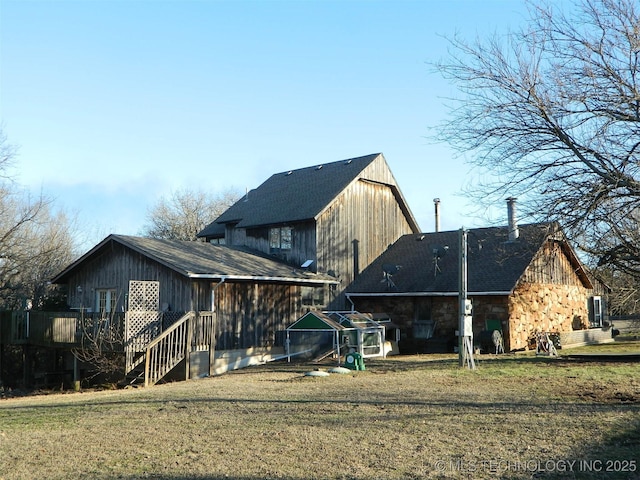 rear view of house featuring stone siding and a lawn