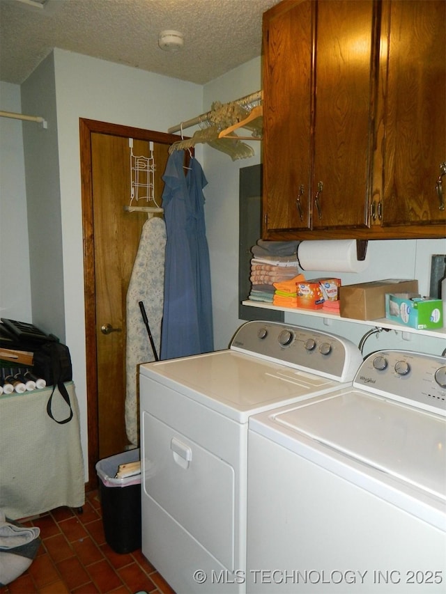 washroom featuring washing machine and dryer, cabinet space, and a textured ceiling