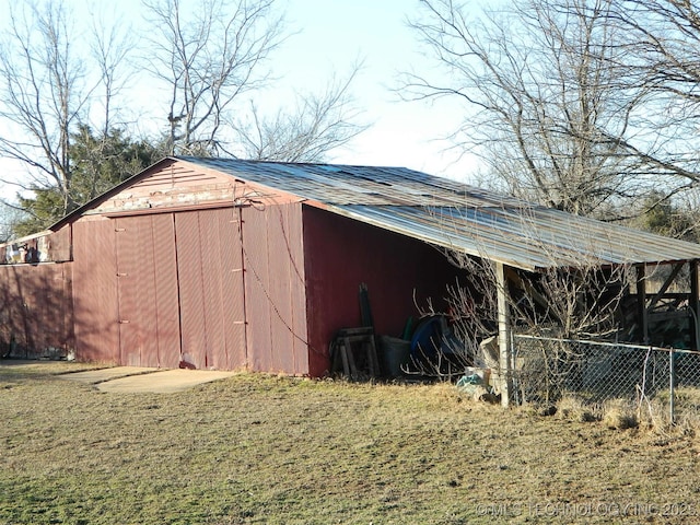 view of pole building featuring a lawn and fence