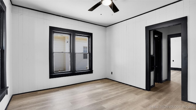 empty room with light wood finished floors, ceiling fan, baseboards, and crown molding