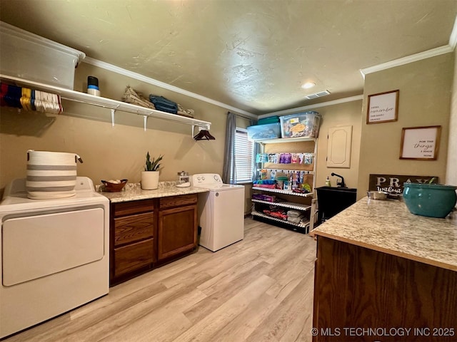 laundry area with light wood finished floors, washer / clothes dryer, ornamental molding, and visible vents