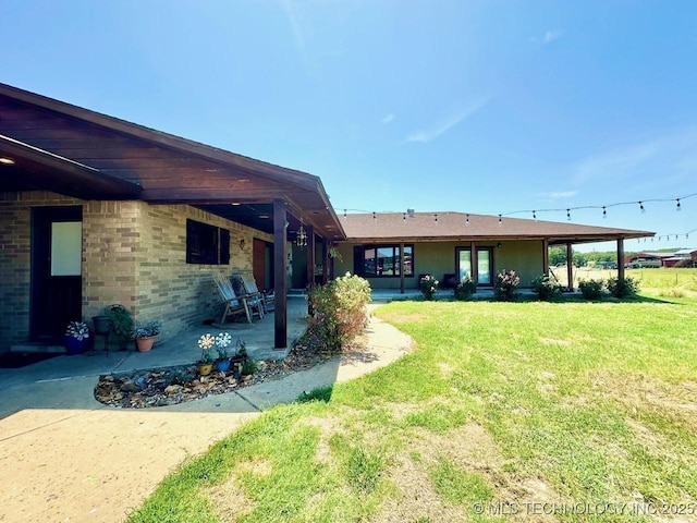 rear view of property featuring a patio area, brick siding, and a lawn