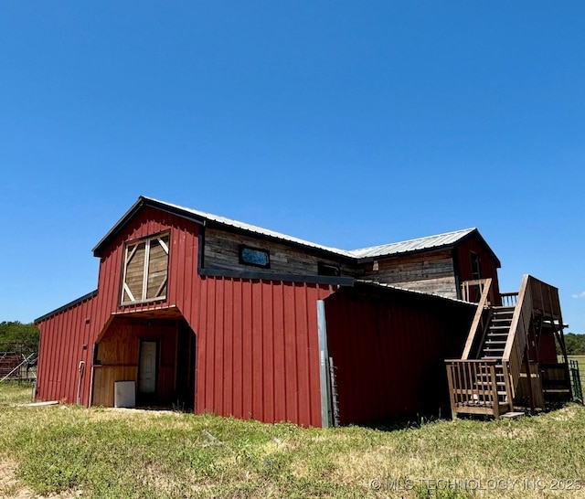 view of property exterior featuring an outbuilding, metal roof, and stairs