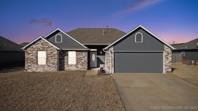 view of front of home with a shingled roof, concrete driveway, a garage, central air condition unit, and brick siding