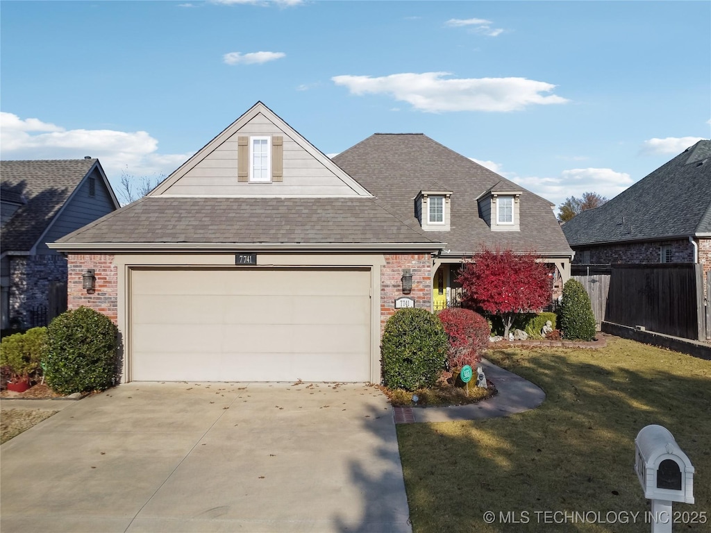 view of front facade featuring driveway, a garage, fence, and brick siding