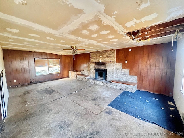 unfurnished living room with wood walls, a fireplace, and unfinished concrete flooring