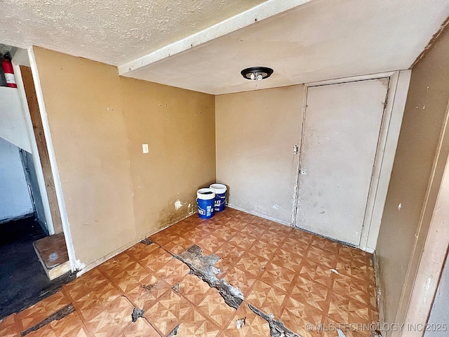 unfurnished room featuring a textured ceiling and tile patterned floors