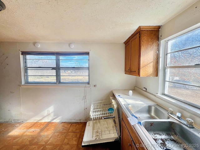 laundry room featuring a textured ceiling, a sink, and cabinet space