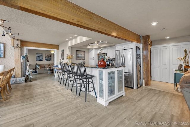 29898 S 566th Rd Unit 411, Afton, OK 74331 - kitchen featuring freestanding refrigerator, a breakfast bar area, dark stone counters, light wood-style flooring, and recessed lighting