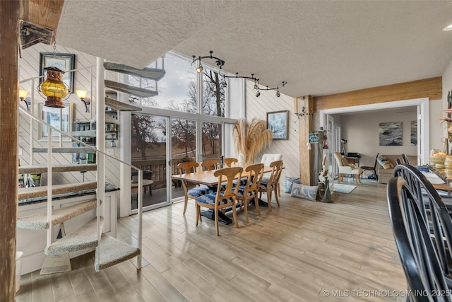 29898 S 566th Rd Unit 411, Afton, OK 74331 - dining room featuring wooden walls, stairs, a wall of windows, wood finished floors, and a textured ceiling