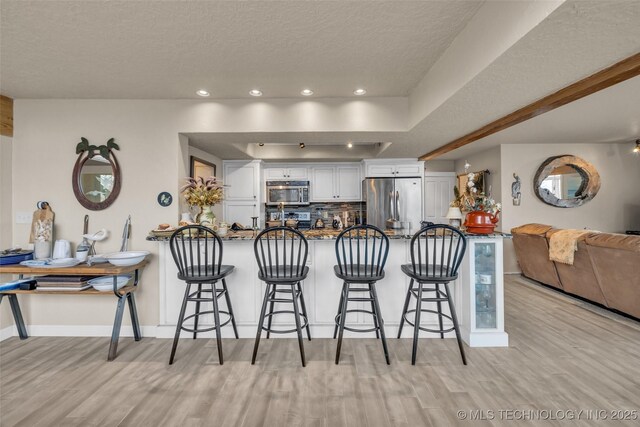 29898 S 566th Rd Unit 411, Afton, OK 74331 - kitchen with appliances with stainless steel finishes, light wood-type flooring, a peninsula, a textured ceiling, and recessed lighting