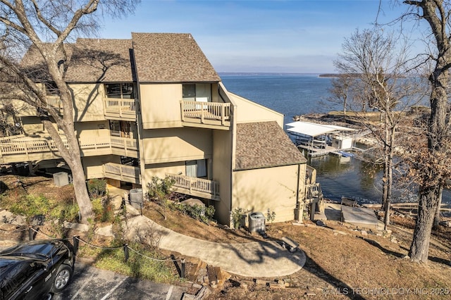 29898 S 566th Rd Unit 411, Afton, OK 74331 - view of home's exterior with a shingled roof, a water view, a balcony, cooling unit, and stucco siding