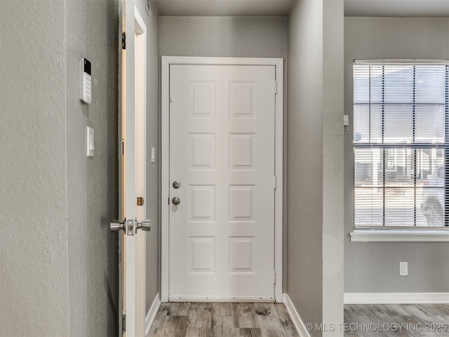 doorway to outside with light wood-style floors and baseboards