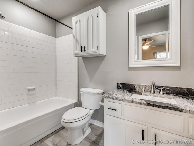 full bath with toilet, wood finished floors, vanity, a ceiling fan, and shower / bathing tub combination