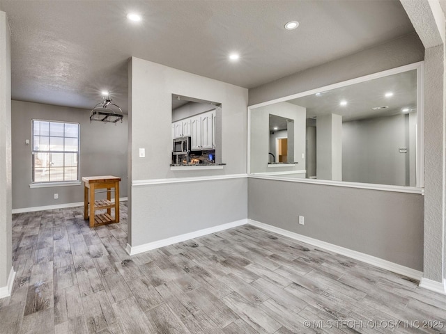 unfurnished room with light wood-style floors, recessed lighting, a textured ceiling, and baseboards