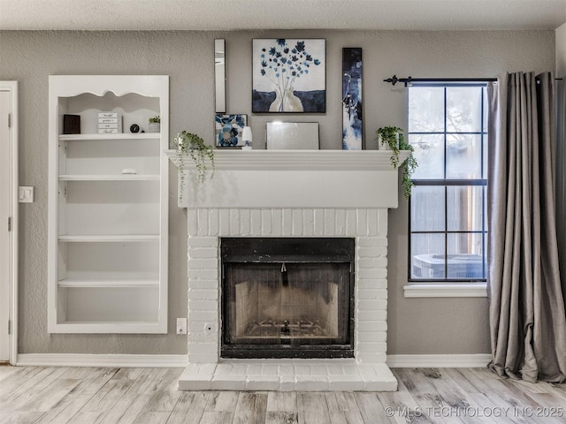 interior details with built in features, a fireplace, baseboards, and wood finished floors