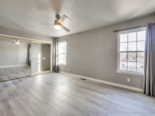 unfurnished bedroom with light wood finished floors, baseboards, visible vents, and a closet