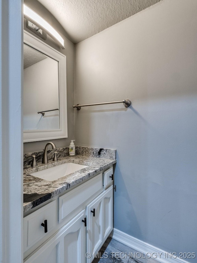 bathroom featuring baseboards, a textured ceiling, and vanity