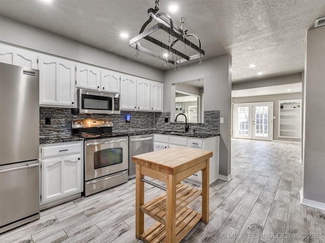 kitchen featuring wood tiled floor, appliances with stainless steel finishes, and white cabinets