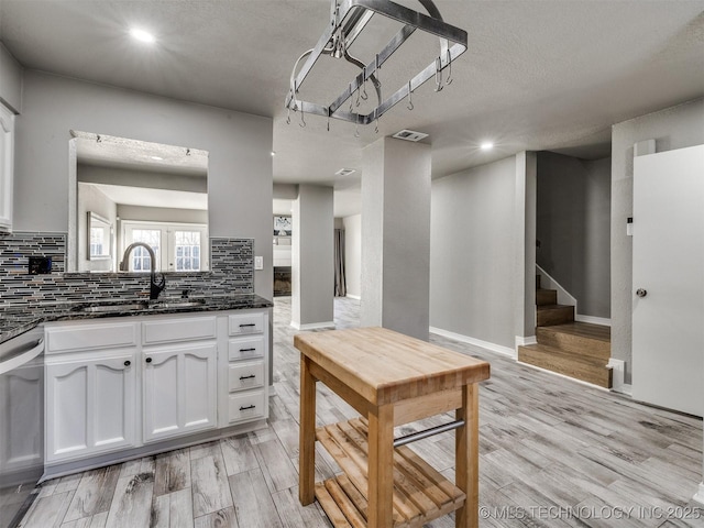 kitchen featuring white cabinets, dishwasher, backsplash, and light wood finished floors