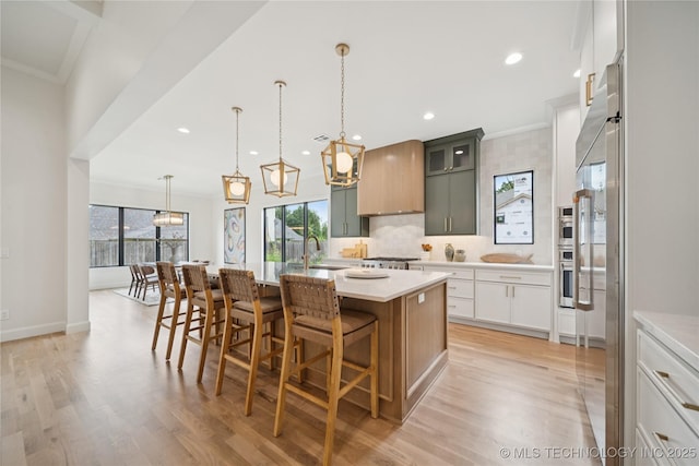 1641 E 32nd St, Tulsa, OK 74105 - kitchen featuring plenty of natural light, light countertops, light wood-type flooring, a kitchen island with sink, and ornamental molding